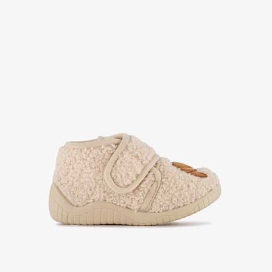 Zijzicht van beige, teddy slof met bruine croissant applicatie en klittenbandsluiting.