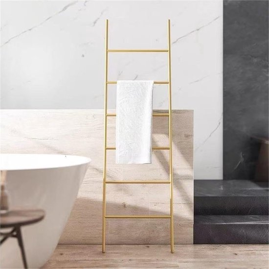 Gouden handdoekladder met een witte handdoek naast een badkuip.