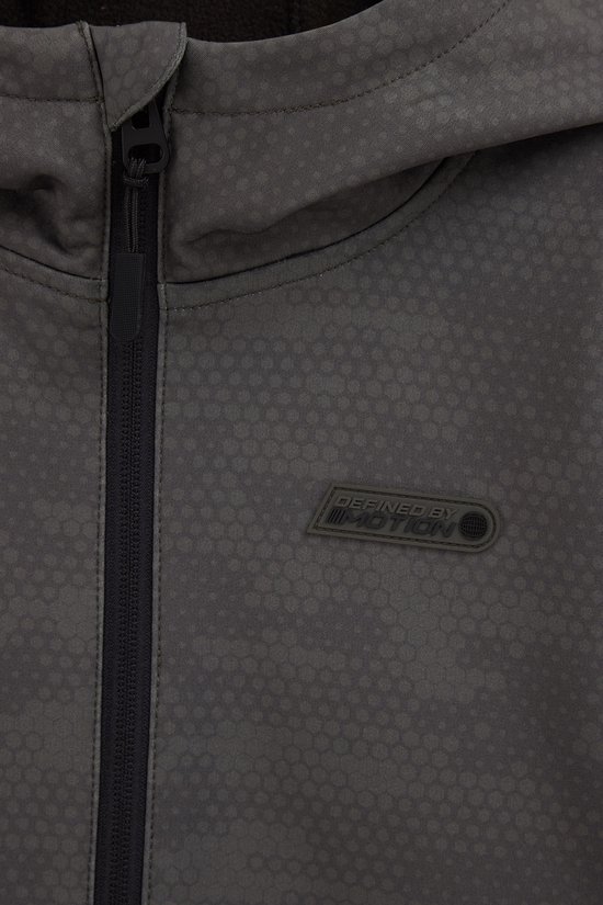 Close-up van de voorkant van een donkergrijze softshell jas met capuchon. De jas heeft een subtiel geometrisch patroon en een logo met tekst 'DEFINED BY MOTION'.