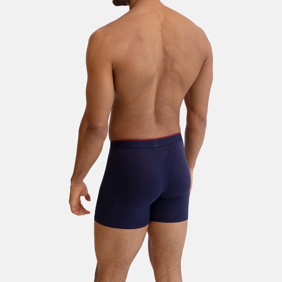 Man in donkerblauwe boxershorts met rode bies aan de tailleband.