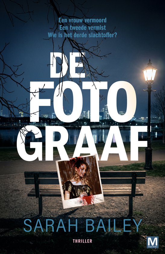 Boekomslag van "De Fotograaf" met op de voorgrond een bankje met daarop een bloederige foto van een vrouw, met op de achtergrond een avondlandschap met stadslichten.