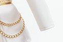 Gedetailleerde foto van de witte rok met gouden kettingen en gouden zigzag riem.