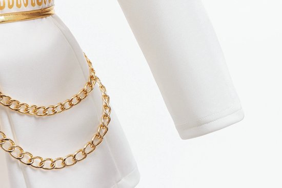 Gedetailleerde foto van de witte rok met gouden kettingen en gouden zigzag riem.