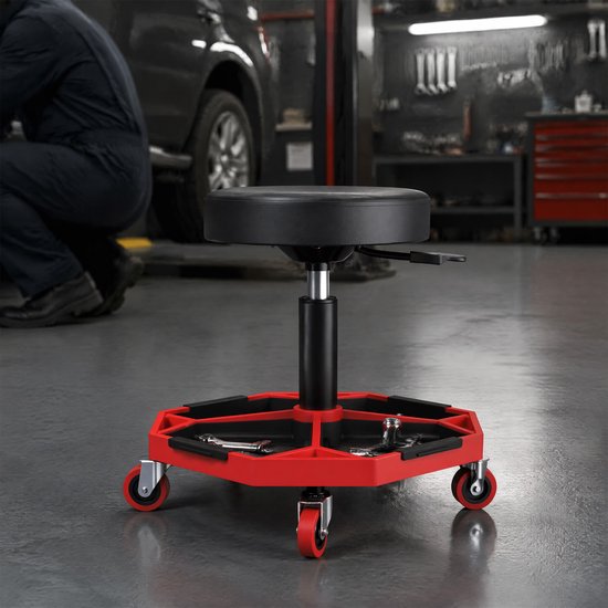 Werkplaatskruk met gereedschapsbak en rode wieltjes in een garage.