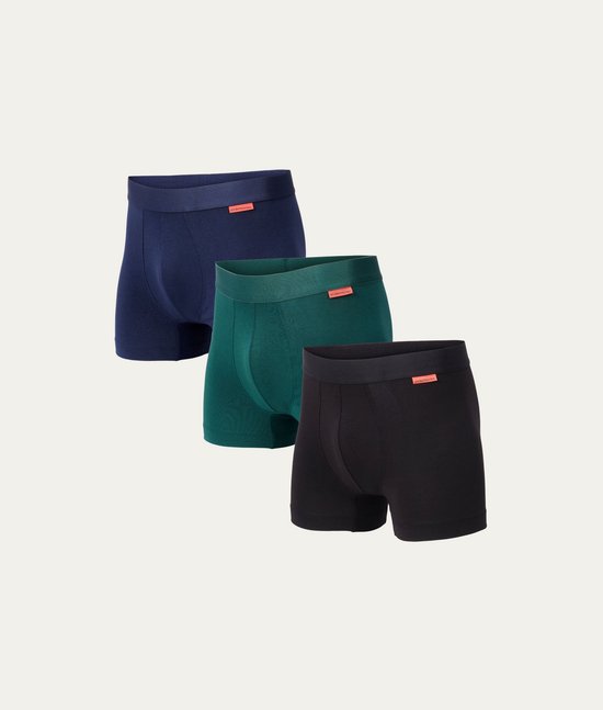 Drie naadloze boxershorts van Tencel in donkere tinten: marineblauw, bosgroen en zwart. Elk met een oranje label.