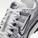 Close-up van de grijze Nike P-6000 sneaker. Zwarte Nike swoosh en 'NIKE' logo op de tong. Witte veters.