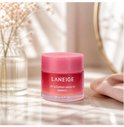 Pot rose Laneige Lip Sleeping Mask EX [Berry] sur une table avec des ombres et un vase.