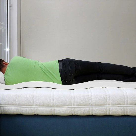 Homme en t-shirt vert allongé sur un surmatelas en mousse à mémoire de forme Nasa blanche avec un dessous bleu.