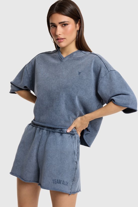Model draagt een blauwe casual top met korte mouwen en een V-hals en een shorts.