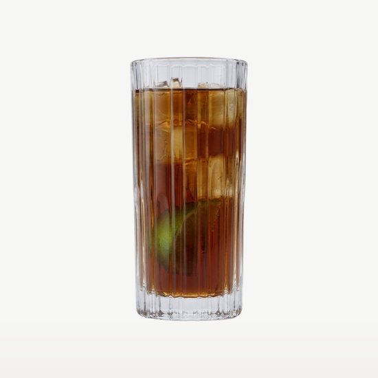 Verre haut et côtelé rempli d'une boisson brune, de glaçons et d'un quartier de citron vert.