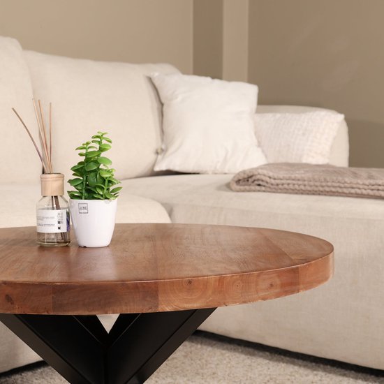 Ronde salontafel van mangohout met een walnootkleurige afwerking, met een plant en geurverspreider.