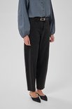 Gedetailleerde foto van een vrouw in een zwart-wit geblokt overhemd en zwarte spijkerbroek met riem.