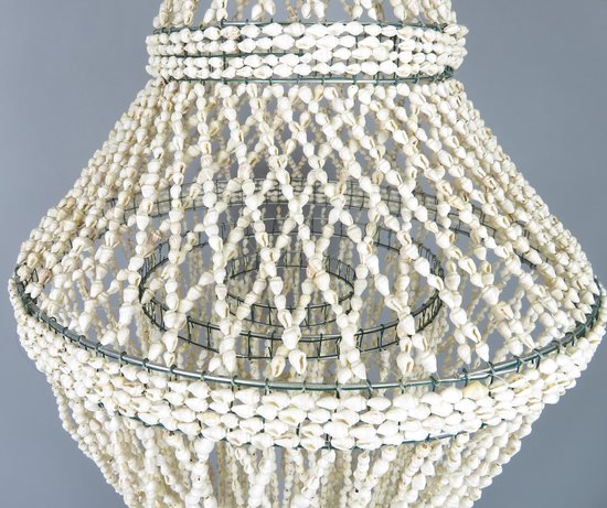 Lamp van witte schelpen op een metalen frame met meerdere lagen schelpen, lichte grijze achtergrond.