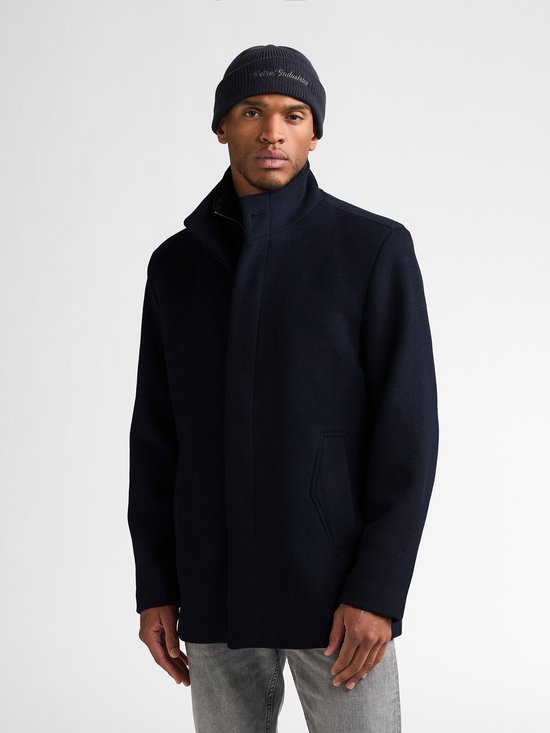 Model draagt een marineblauwe wollen mantel en een bijpassende beanie met 'Petrol Industries' tekst.