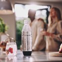 Sodastream fles van helder plastic met zwarte dop en onderkant, naast een glas met aardbeien.