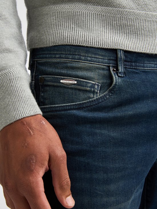 Close-up van een donkerblauwe jeans met Petrol Industries logo op de zak.