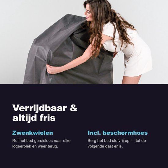 Vrouw in witte jurk en zwarte laarzen stopt een bed in een grijze beschermhoes. Het bed heeft zwenkwielen voor verrijdbaarheid.