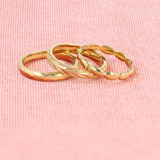 Drie gouden ringen op elkaar, met een golfpatroon, een decoratieve gravure en een ring met kleine bolletjes.