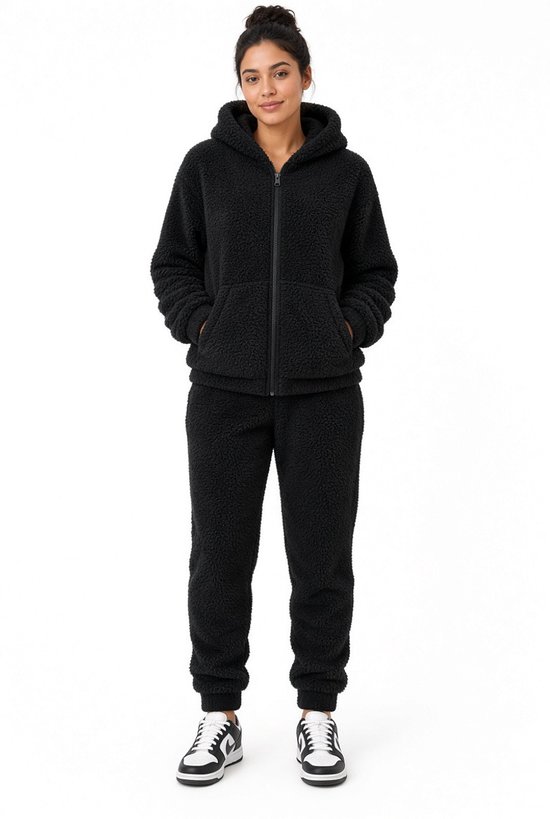 Vrouw in zwart teddy joggingpak, voorkant. Fleece vest met capuchon en joggingbroek.