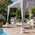 Een gestreepte witte partytent met grijze strepen, zittend op een terras bij een zwembad, met witte meubels. Vier witte, ronde voeten ondersteunen de tent.