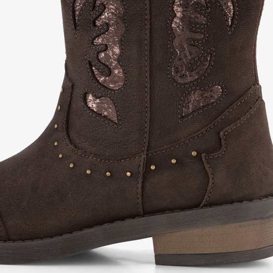 Detail van donkerbruine suède cowboylaars met gouden studs en opgestikte patronen.