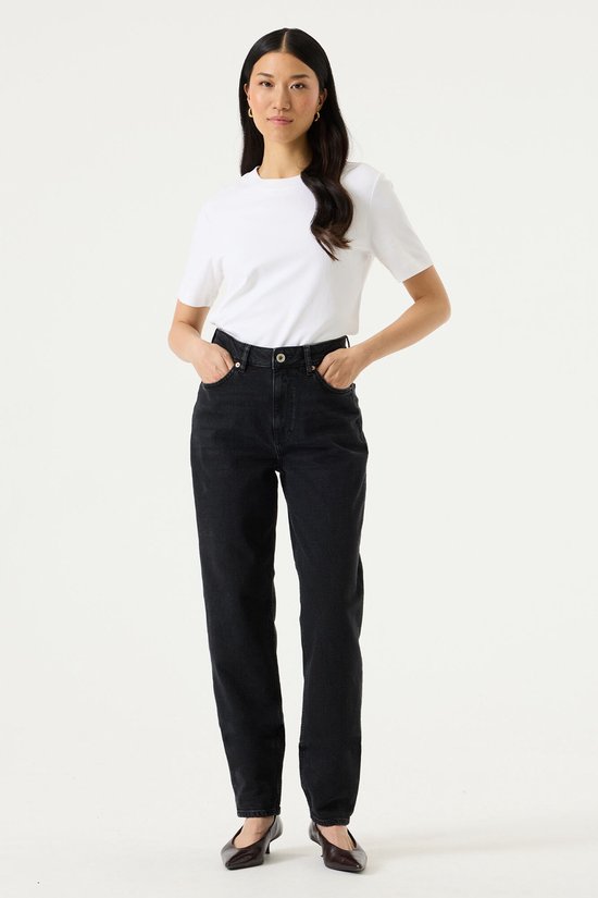 Model draagt zwarte mom fit jeans en een wit T-shirt.