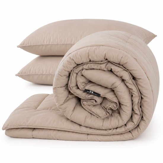 Een beige dekbed is opgerold, met twee beige kussens op de achtergrond.