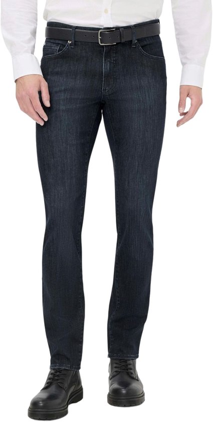 Man in donkerblauwe jeans, wit overhemd met opgerolde mouwen en zwarte riem.