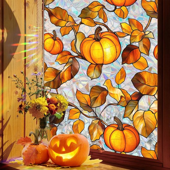 Raamfolie met gedroogde herfstbladeren en pompoenen in warme oranje en bruine tinten. Een uitgeholde halloweenpompoen staat voor het raam.