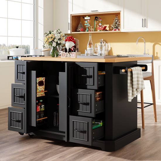 Îlot de cuisine noir avec plateau en bois dans une cuisine. Portes et tiroirs ouverts avec des provisions.