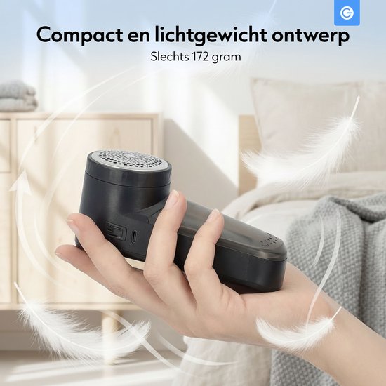 Hand met zwarte, compacte en lichte pluizenverwijderaar, met veren die rondzweven.