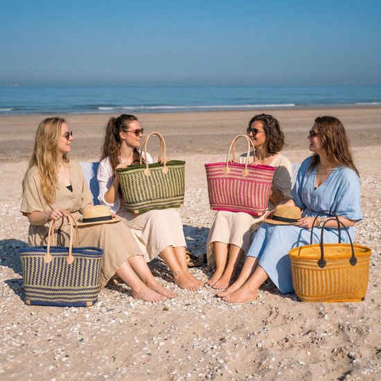 Vier vrouwen zitten op het strand met rieten manden in verschillende kleuren: blauw, groen, roze en geel.