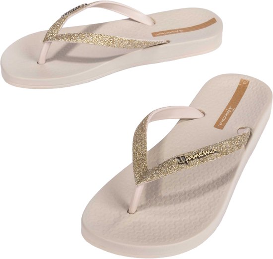 Paar beige Ipanema teenslippers met glitterbandjes op zwarte achtergrond.