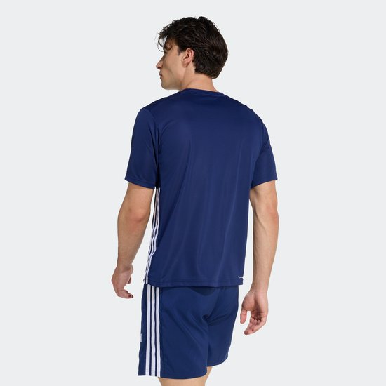 Man doet een oefening met een bal op de schouder, draagt donkerblauw sport T-shirt en korte broek.