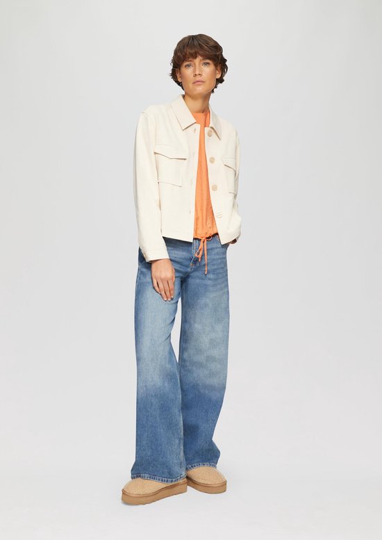 Model draagt een oranje s.Oliver blouse en blauwe jeans.