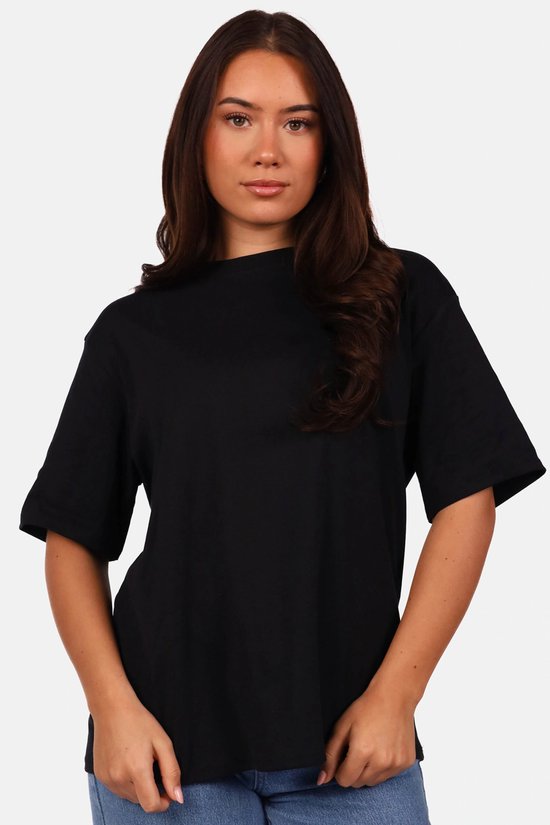 Model draagt een oversized zwart t-shirt met korte mouwen.