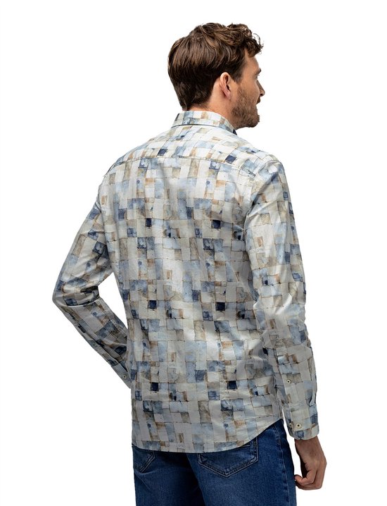 Man van achteren gezien, draagt een wit overhemd met blauw en bruin blokjespatroon en jeans.