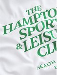 Close-up van de groene tekst 'THE HAMPTONS SPORTS & LEISURE CLUB' op een wit katoenen T-shirt.