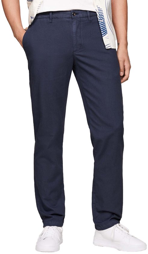 Homme portant un pantalon chino bleu marine et une chemise blanche à imprimé bleu.