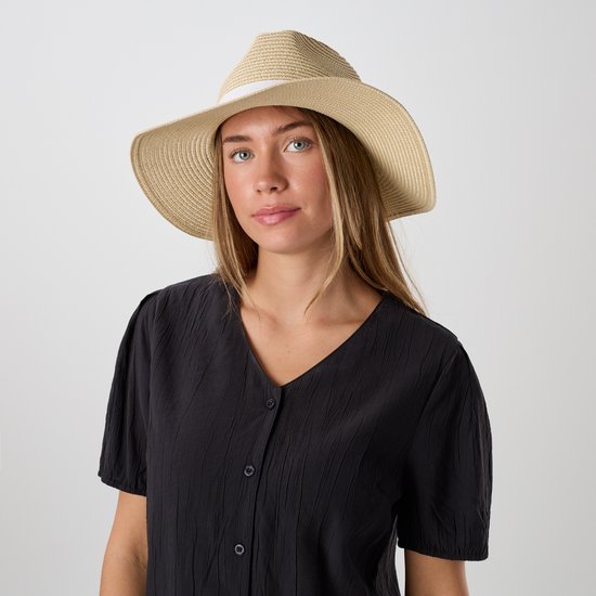 Close-up van model in zwarte blouse met knoopjes en strooien hoed.