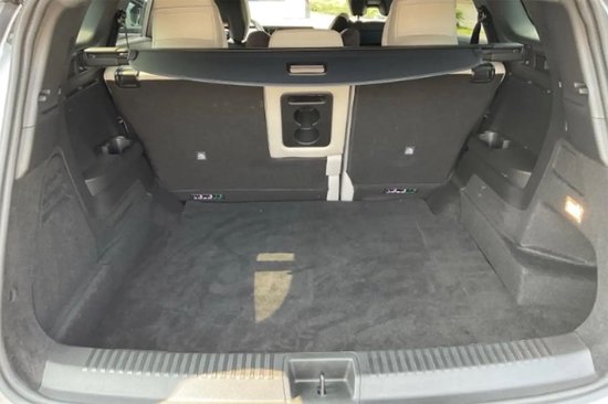 Lege, donkergrijze kofferbak van een auto met opgevouwen achterbank.
