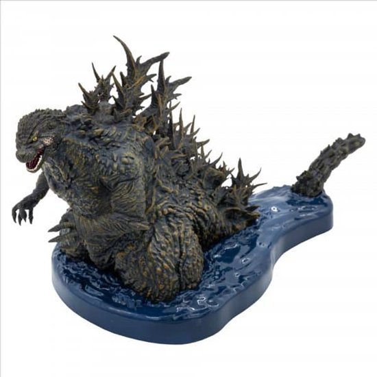 Grijze Godzilla figuur met scherpe rugplaten, op een blauwe waterbasis, van opzij gezien.