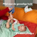 Baby op een oranje bank, met een hand die een blauwe doek vasthoudt. Baby houdt een waterwipe vast. Tekst "Mild voor de gevoelige huid" en "0% microplastics".