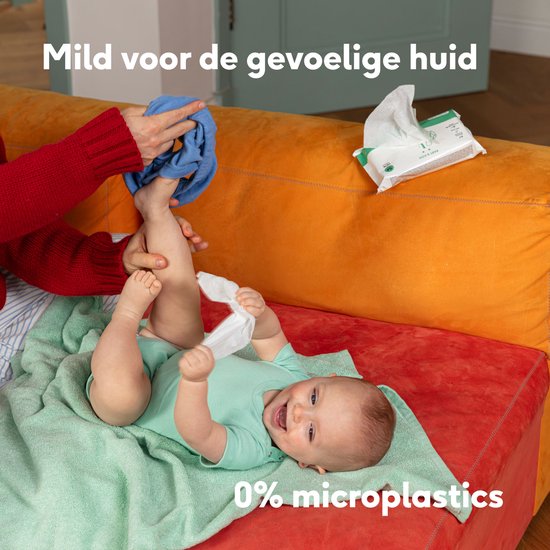 Baby op een oranje bank, met een hand die een blauwe doek vasthoudt. Baby houdt een waterwipe vast. Tekst "Mild voor de gevoelige huid" en "0% microplastics".