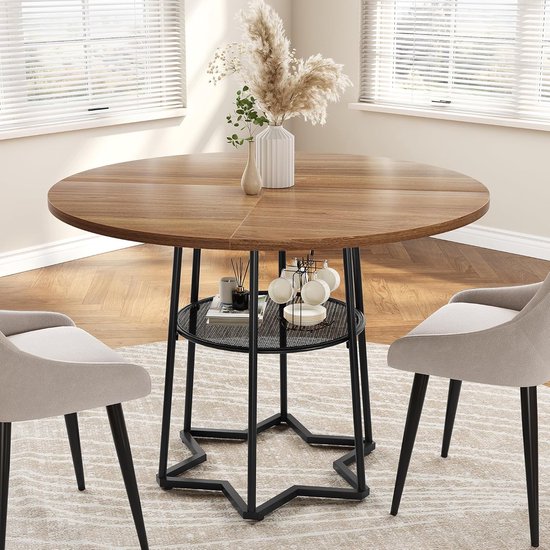 Table ronde brune avec piètement noir en étoile et étagère de rangement avec tasses et vase en herbe de pampa.