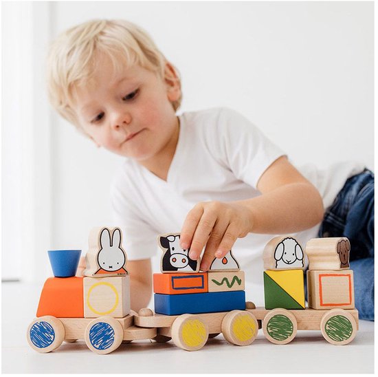 Jongen speelt met houten trein met Miffy, koe, schaap en hond.
