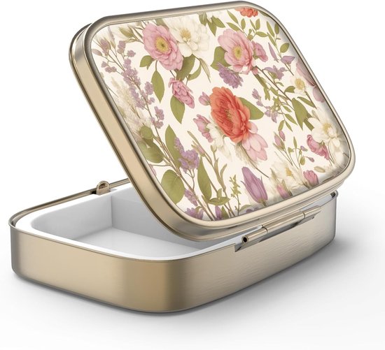 Boîte à pilules dorée avec un couvercle orné d'un imprimé floral aquarelle aux tons roses, rouges et violets sur fond crème.