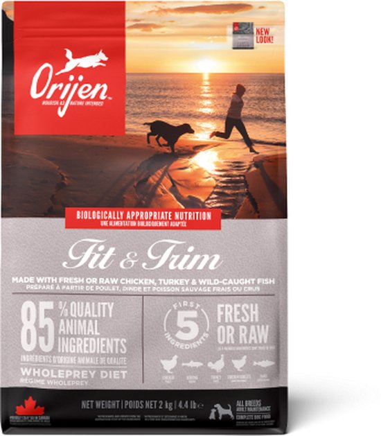 Orijen Fit & Trim hondenvoer zak (2 kg) met afbeelding van een vrouw en hond op het strand bij zonsondergang.
