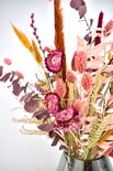 Boeket droogbloemen met roze, paarse en oranje tinten, waaronder helichrysum en pampasgras.