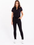Model met zwarte broek met strikceintuur en zwarte blouse met V-hals.
